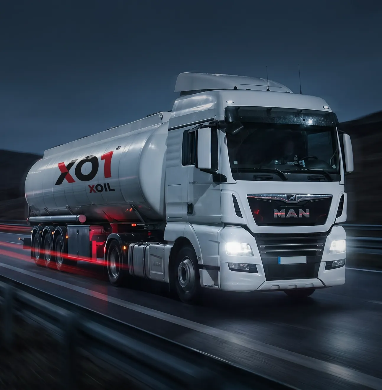 XO1 — biała cysterna na nocnej autostradzie, czerwone smugi świateł