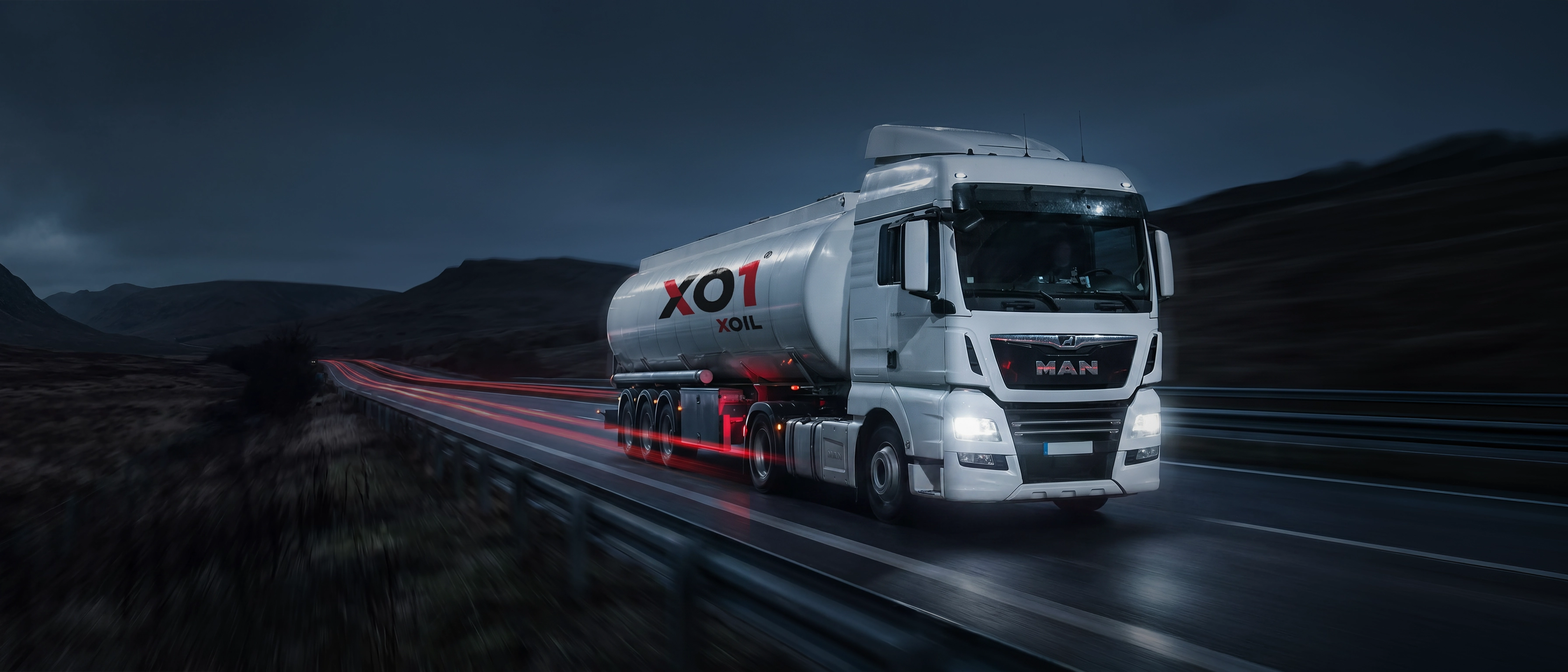 XO1 — biała cysterna na nocnej autostradzie, czerwone smugi świateł